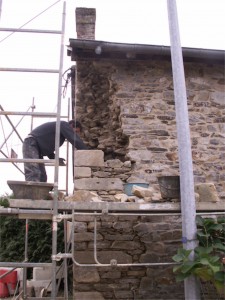 Hugo Gardrel maçon pierre reprend l'angle du mur en pierre/EIRL Terre Crue