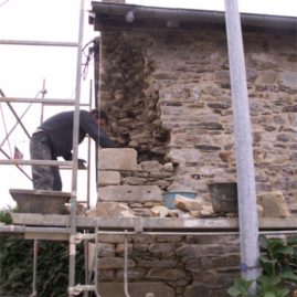 Hugo Gardrel maçon pierre reprend l'angle du mur en pierre/EIRL Terre Crue